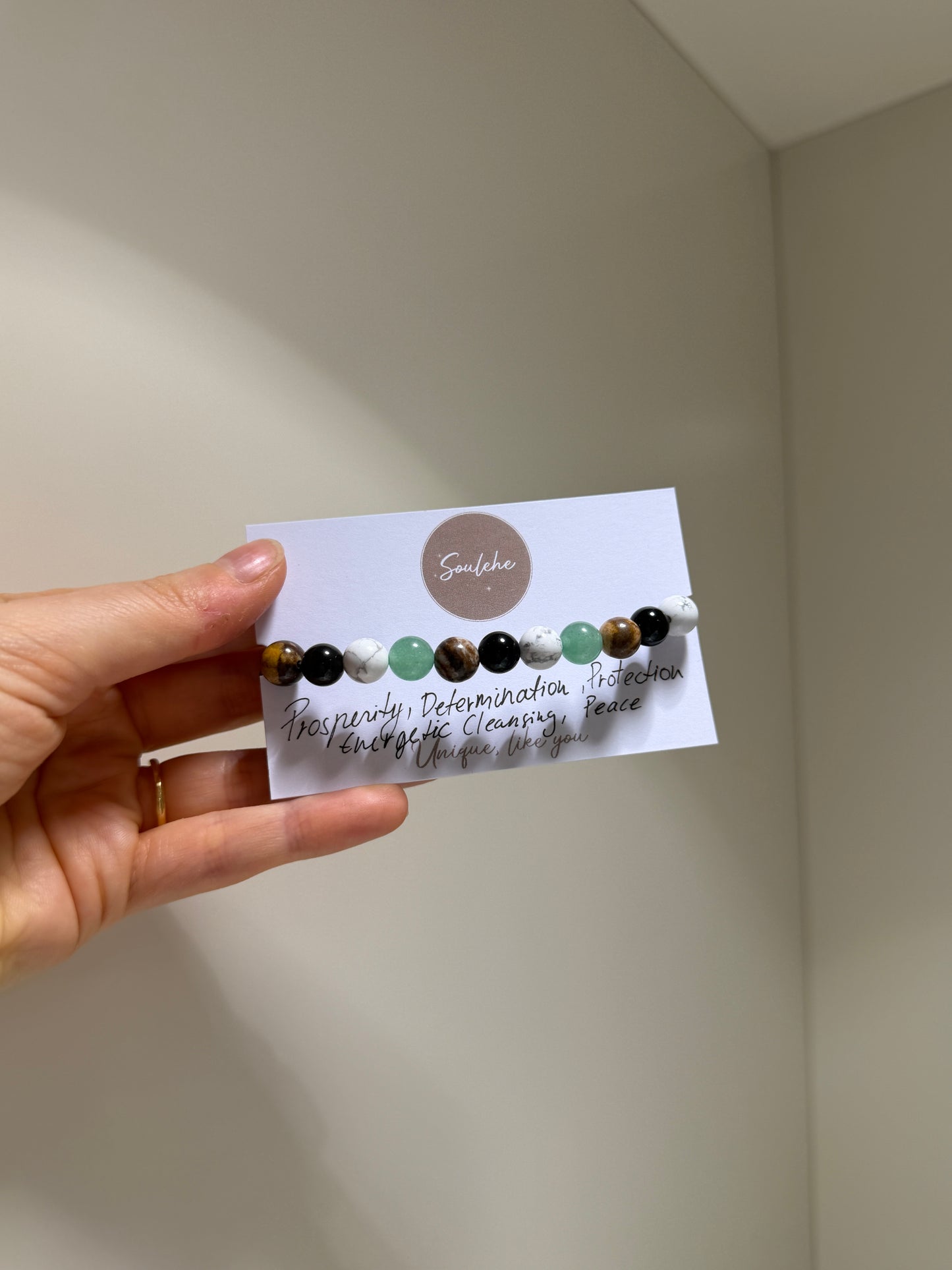 Hand holding a card with a set of beaded hair clips on a plain background