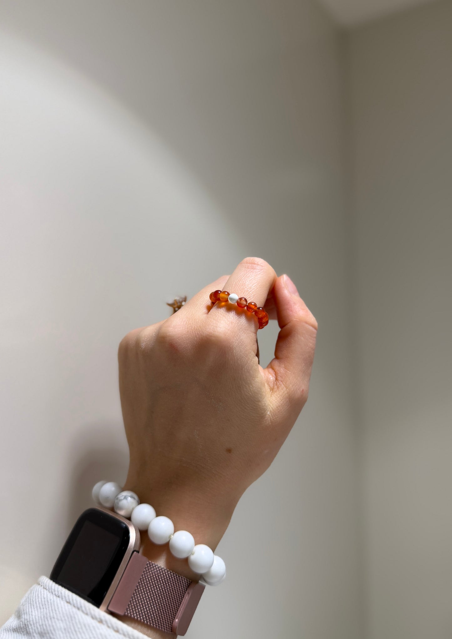 Hand wearing a bracelet with a neutral background