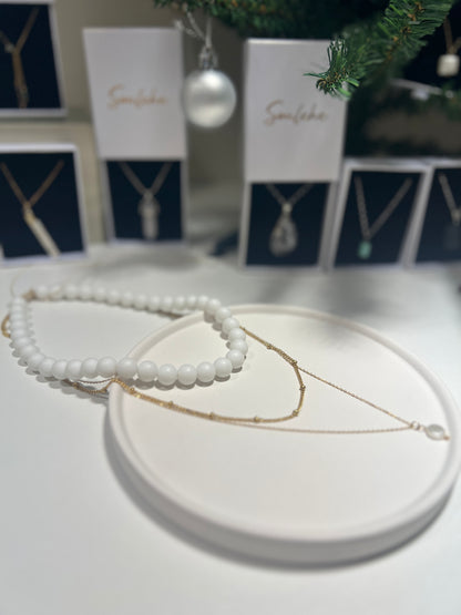Jewelry display with necklaces on a white surface, featuring 'Sunshine' cards in the background.