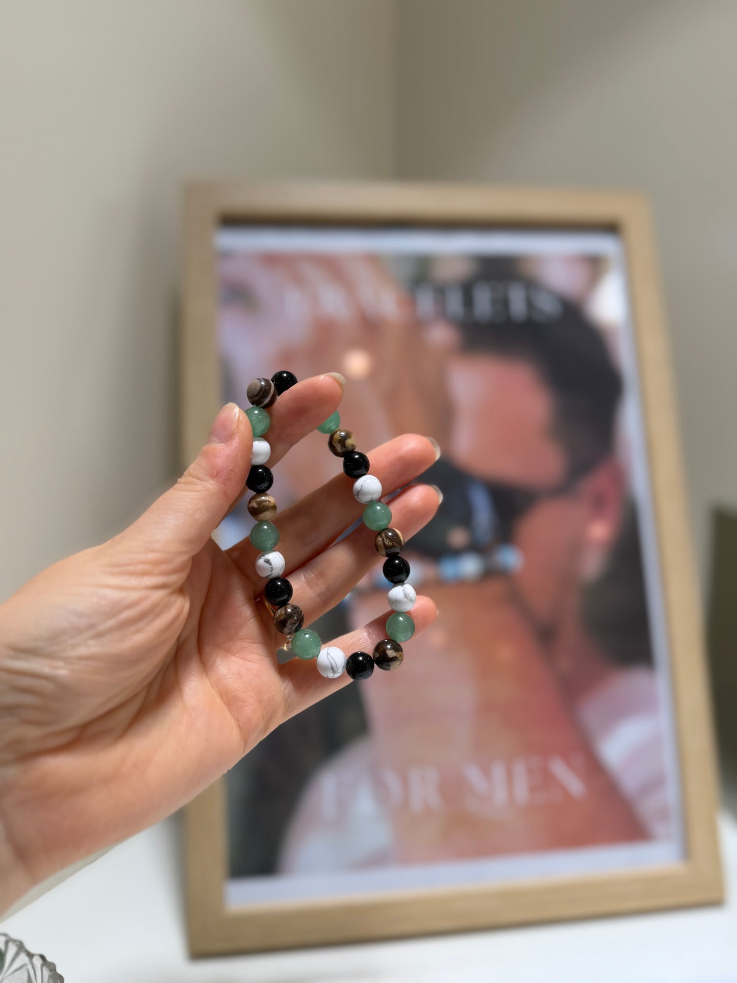 Hand holding a beaded bracelet in front of a blurred magazine cover