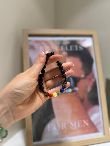 Hand holding a beaded bracelet with a blurred magazine in the background