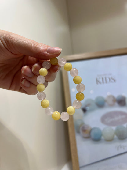 Hand holding a bracelet with pastel beads in front of a framed picture
