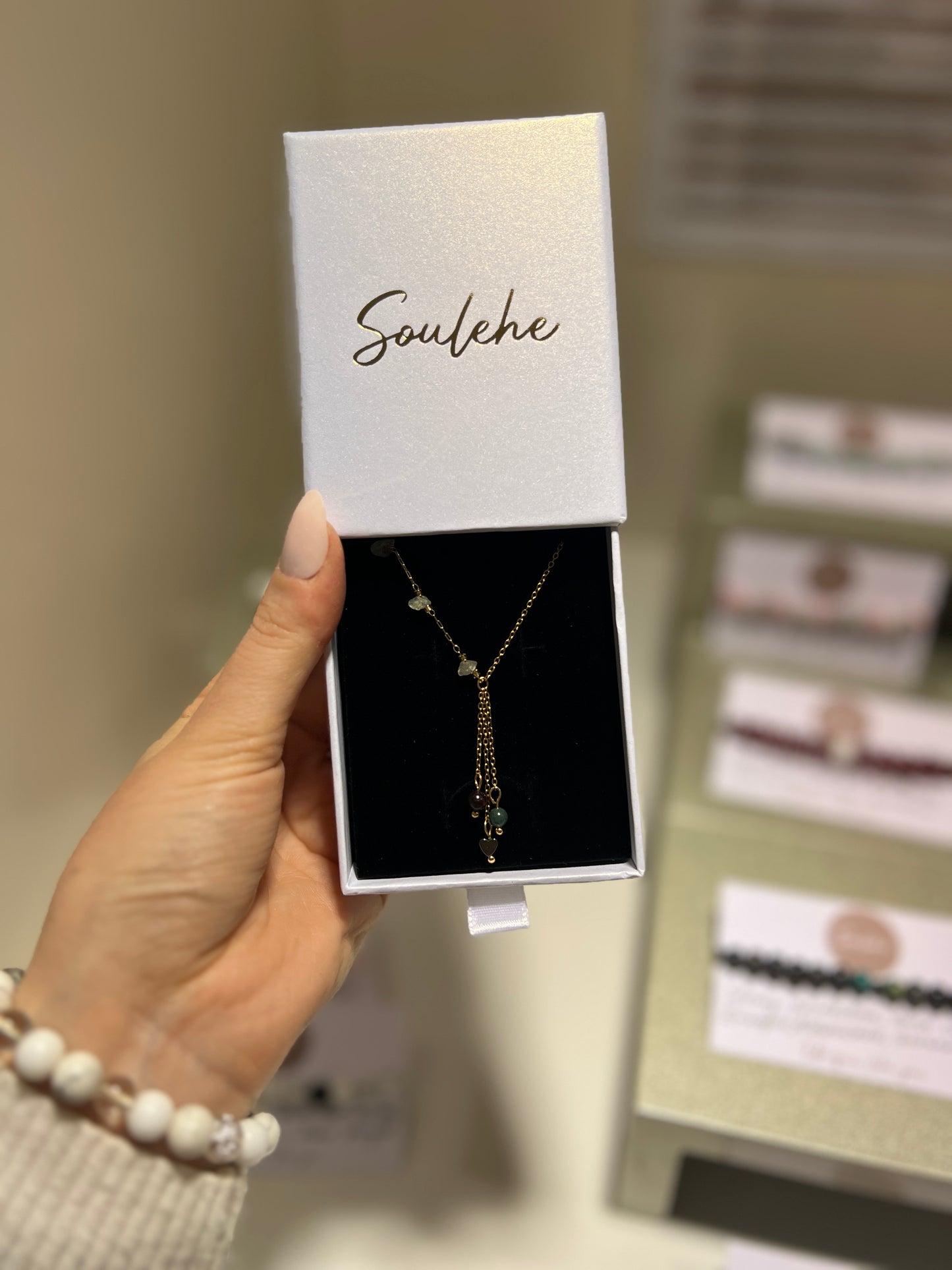 Necklace in a 'Soulehe' box held by a hand with a blurred background