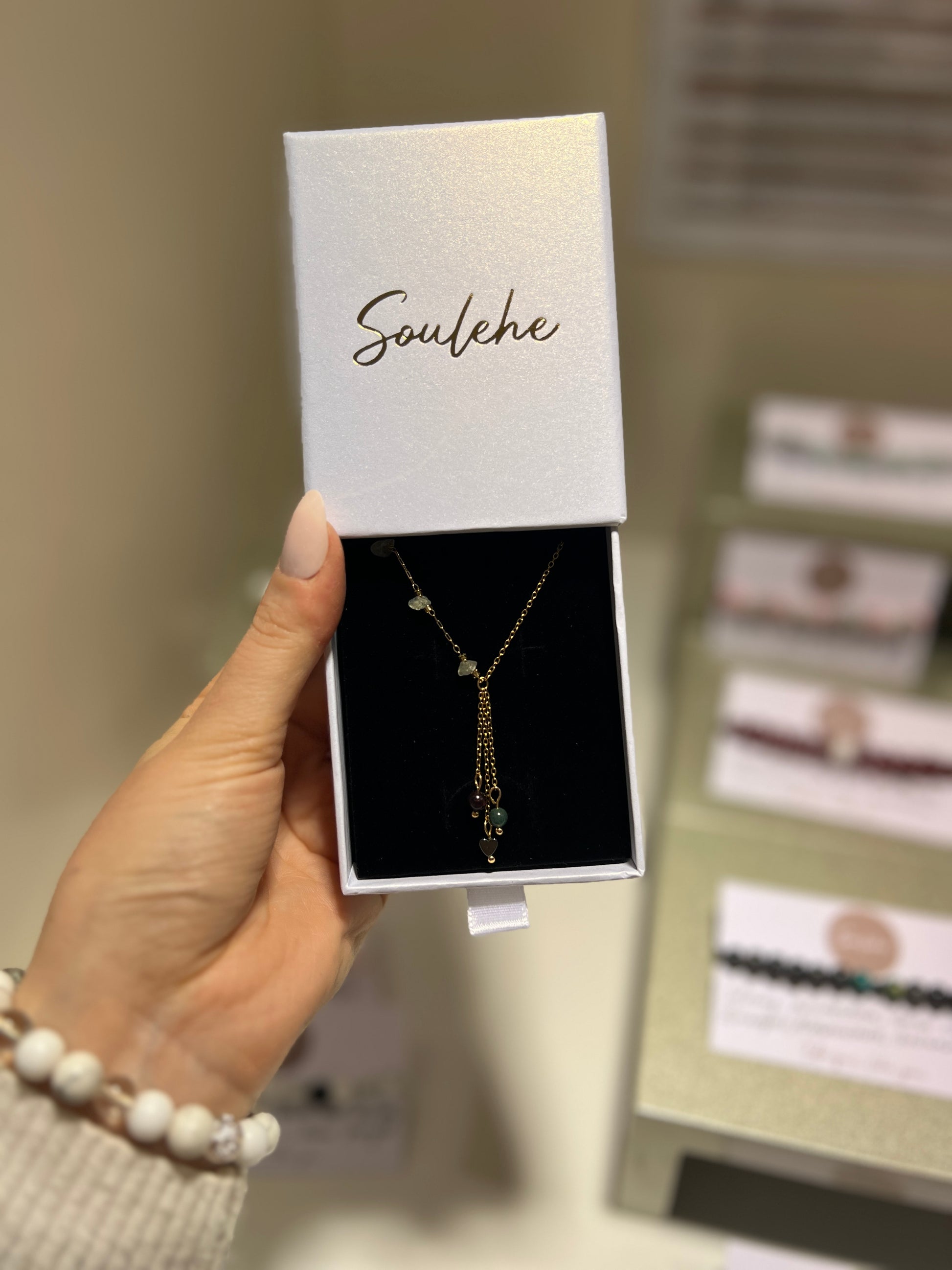 Necklace in a 'Soulehe' box held by a hand with a blurred background