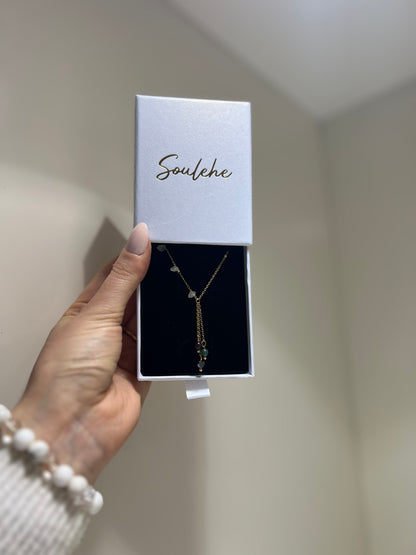 Necklace in a 'Soulehe' box held by a hand against a neutral background