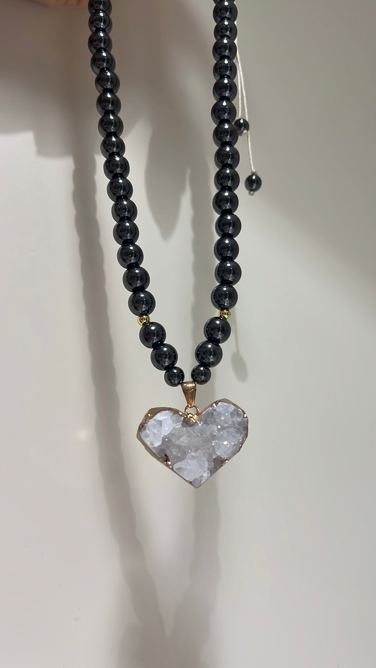 Necklace with black beads and a heart-shaped crystal pendant on a neutral background
