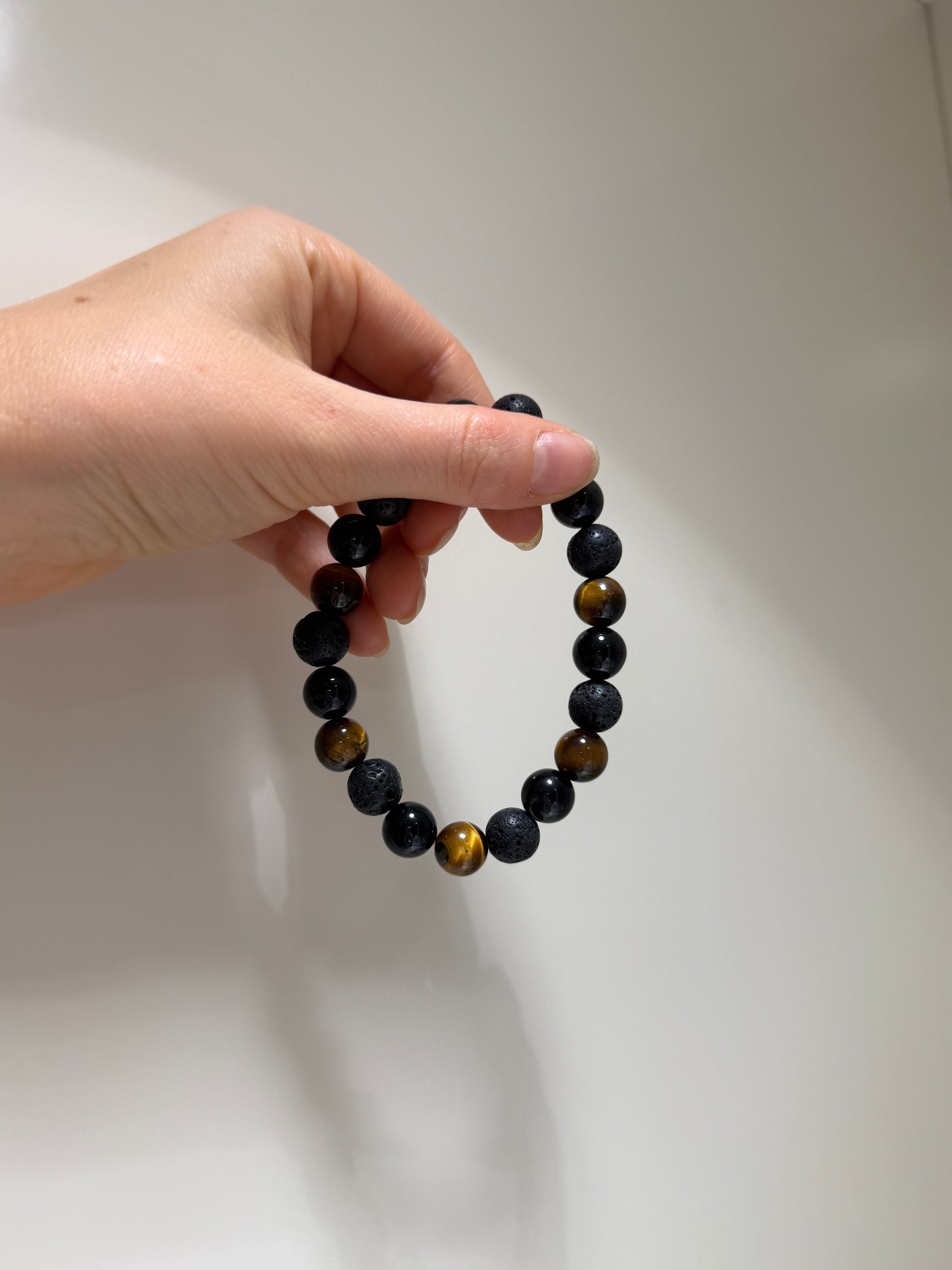 Hand holding a beaded bracelet against a plain background