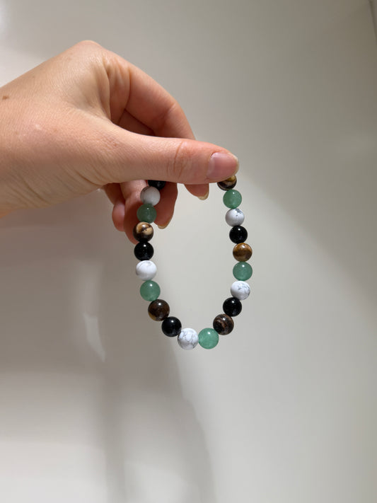 Hand holding a beaded bracelet with multicolored beads against a plain background