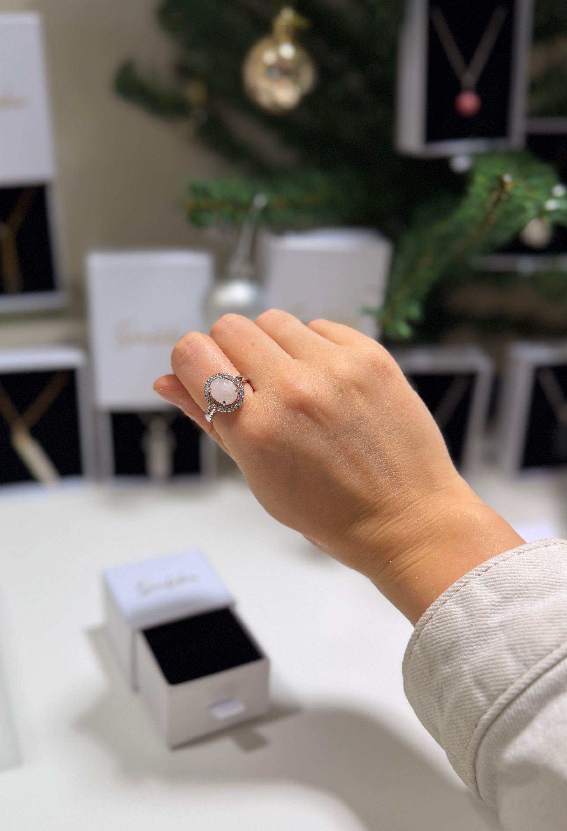 Hand wearing a ring with a blurred jewelry store background
