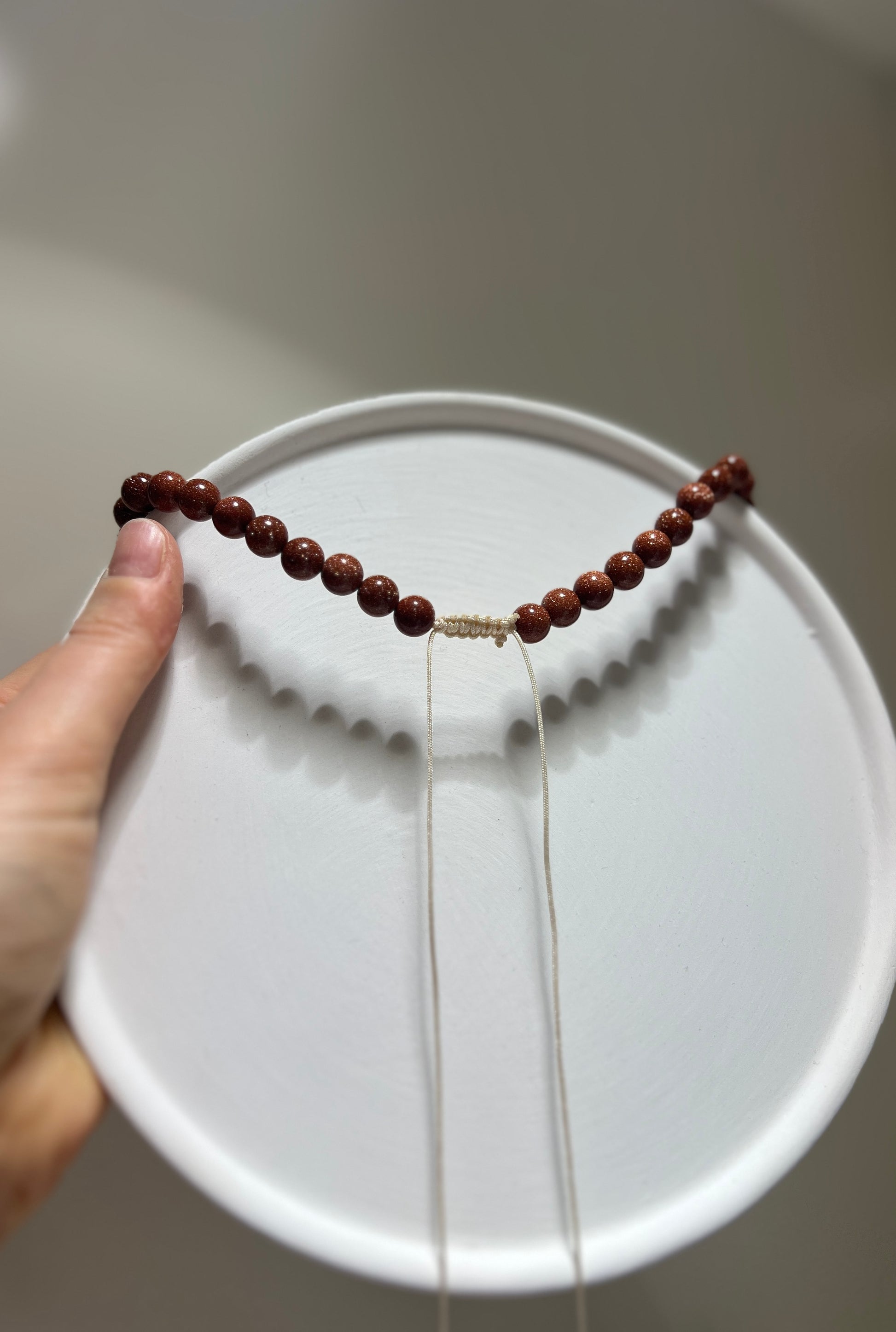 Hand holding a beaded necklace against a plain background