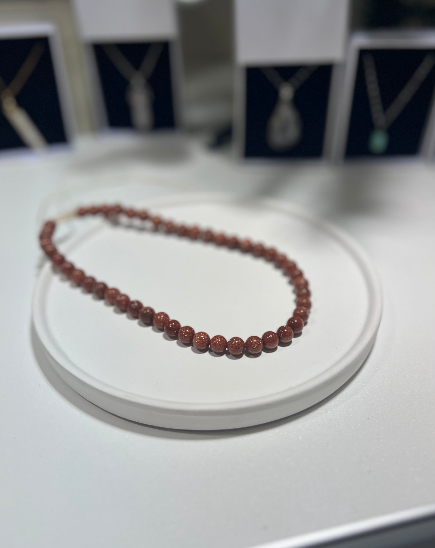 Beaded necklace on a white stand with blurred background