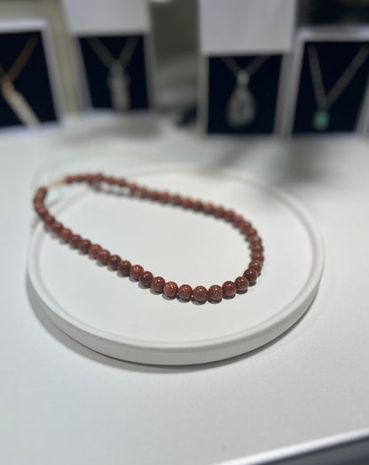 Beaded necklace on a white stand with blurred background