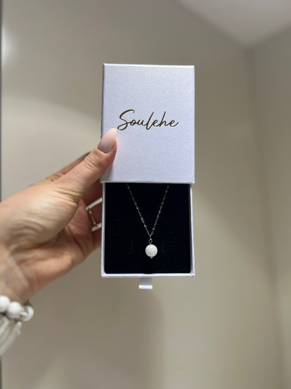 Necklace in a 'Soulehe' box held by a hand against a neutral background