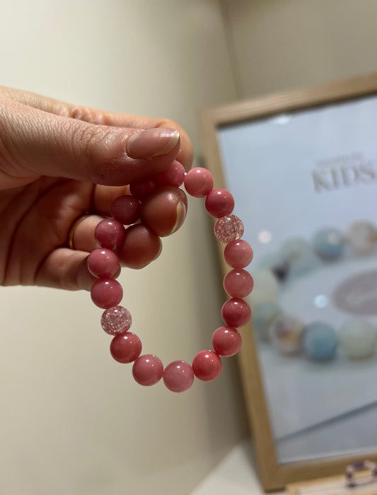 Pink beaded bracelet held by a hand with a blurred background
