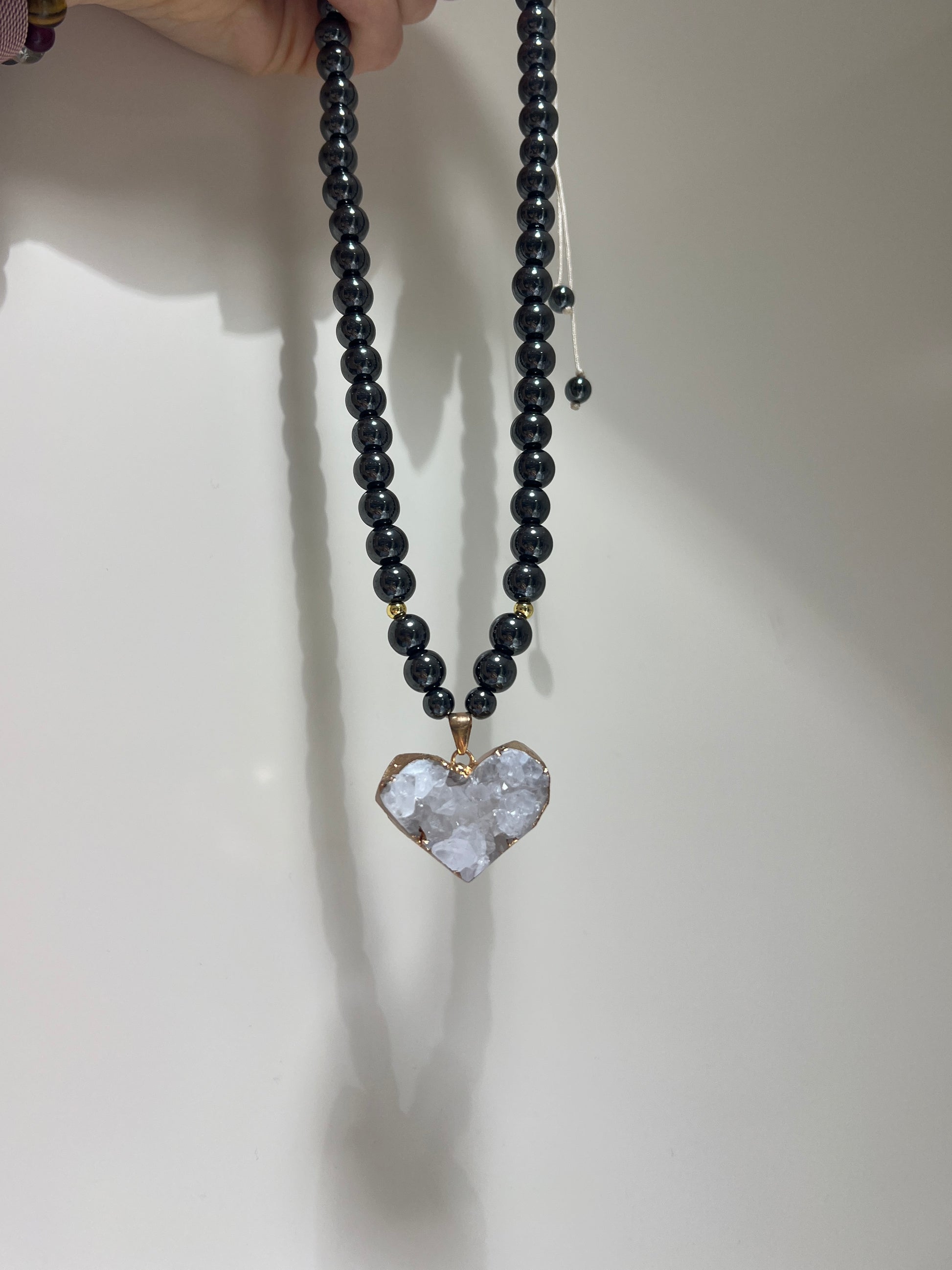 Necklace with black beads and a heart-shaped crystal pendant on a white background