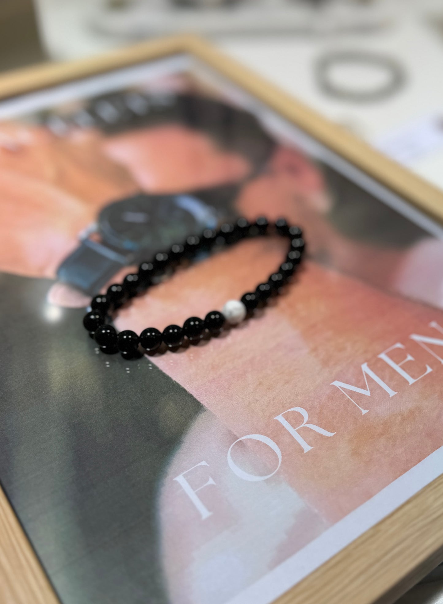 Black beaded bracelet on a magazine with 'For Men' text