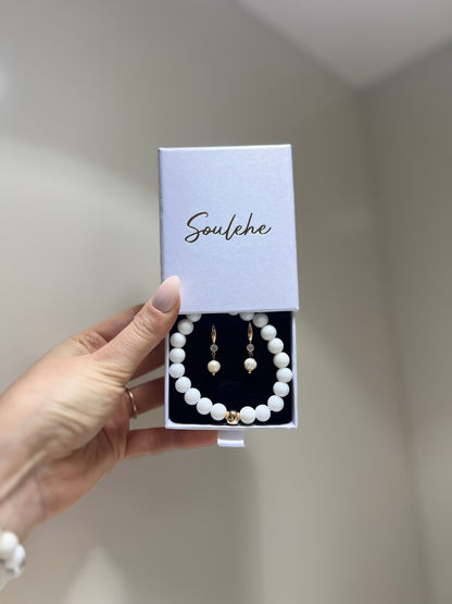 Hand holding a jewelry set with 'Soulehe' packaging against a neutral background