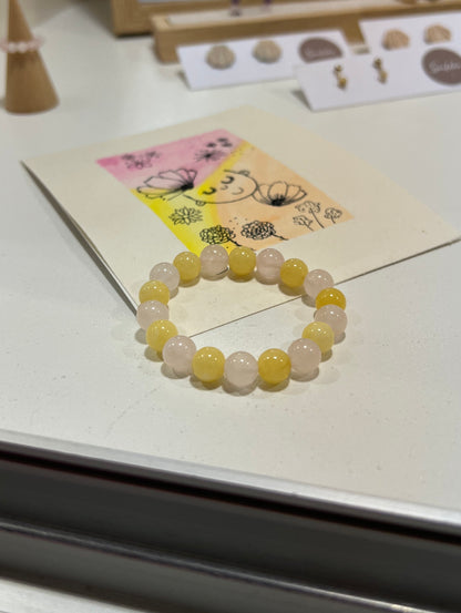 Beaded bracelet on a white surface with a small card in the background