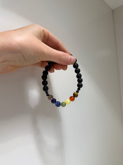 Hand holding a beaded bracelet with multicolored beads on a light background