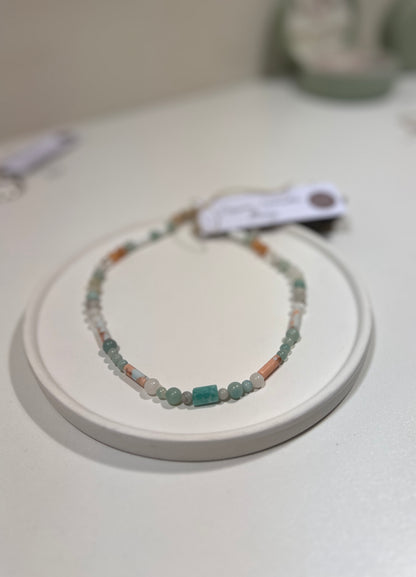 Beaded necklace on a white stand with a blurred background