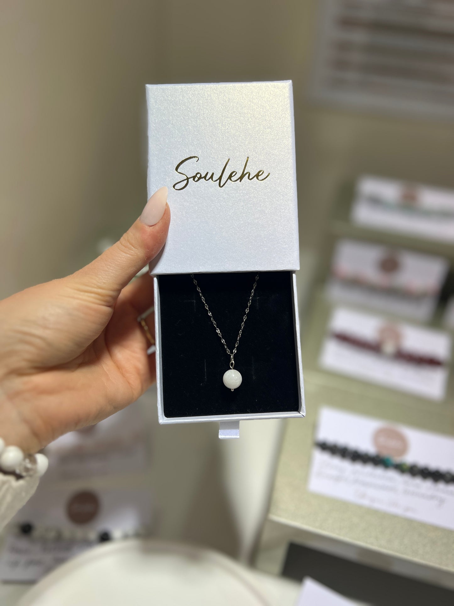 Necklace in a 'Soulehe' box held by a hand with a blurred background