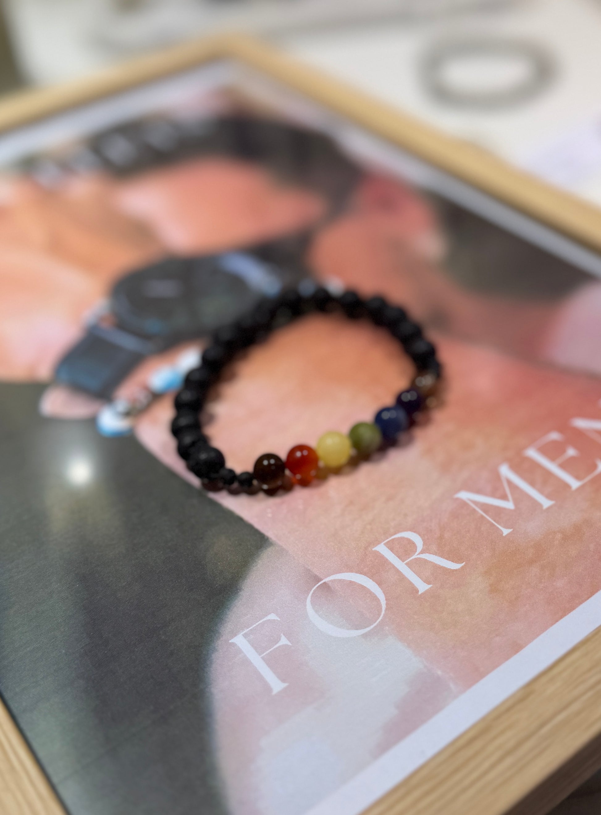 Close-up of a beaded bracelet on a magazine with 'For Men' text.