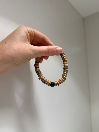 Hand holding a wooden beaded bracelet against a white background