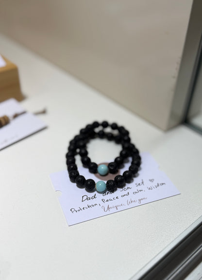 Black beaded bracelets with turquoise stones on a card with text, placed on a light surface.