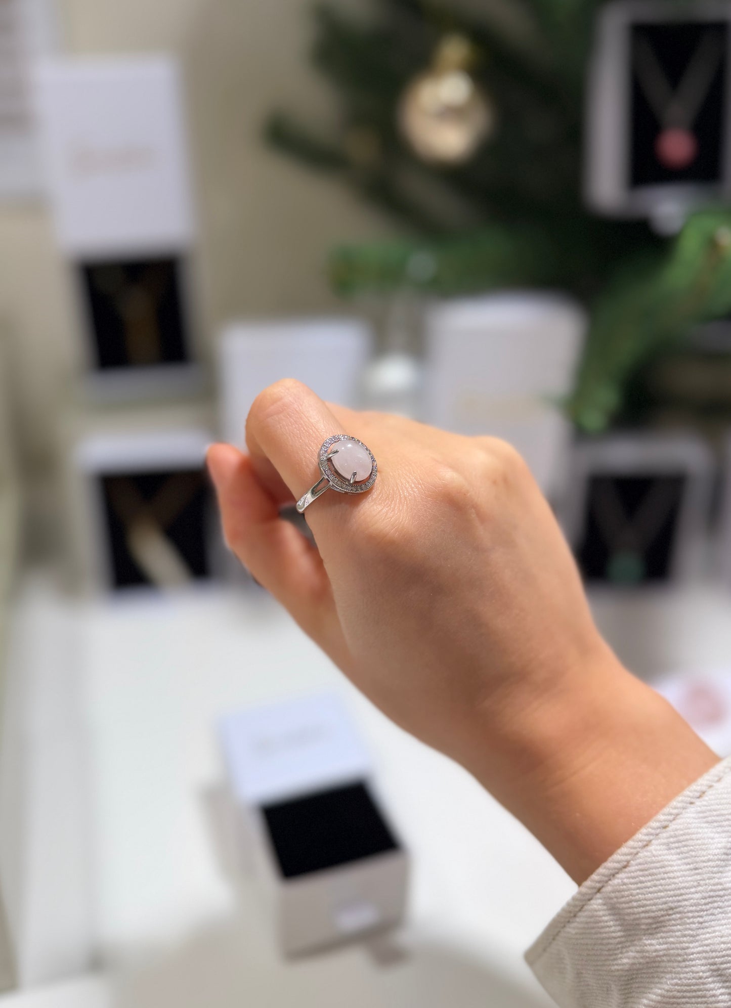 Hand wearing a ring with a blurred jewelry store background