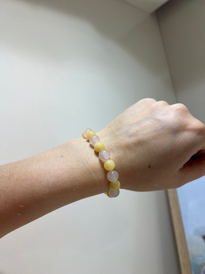 Hand wearing a bracelet with yellow beads on a light background