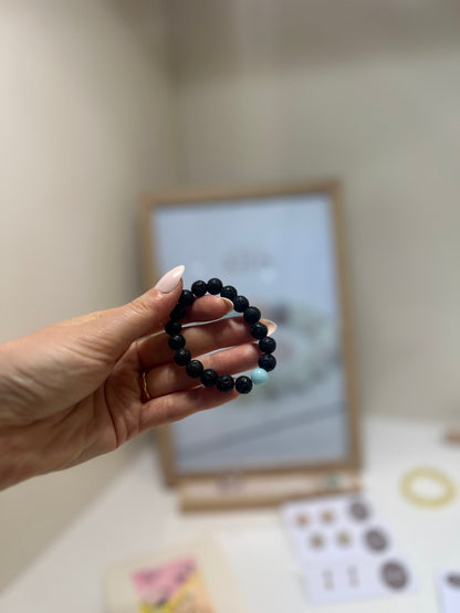Hand holding a black beaded bracelet with a blurred background