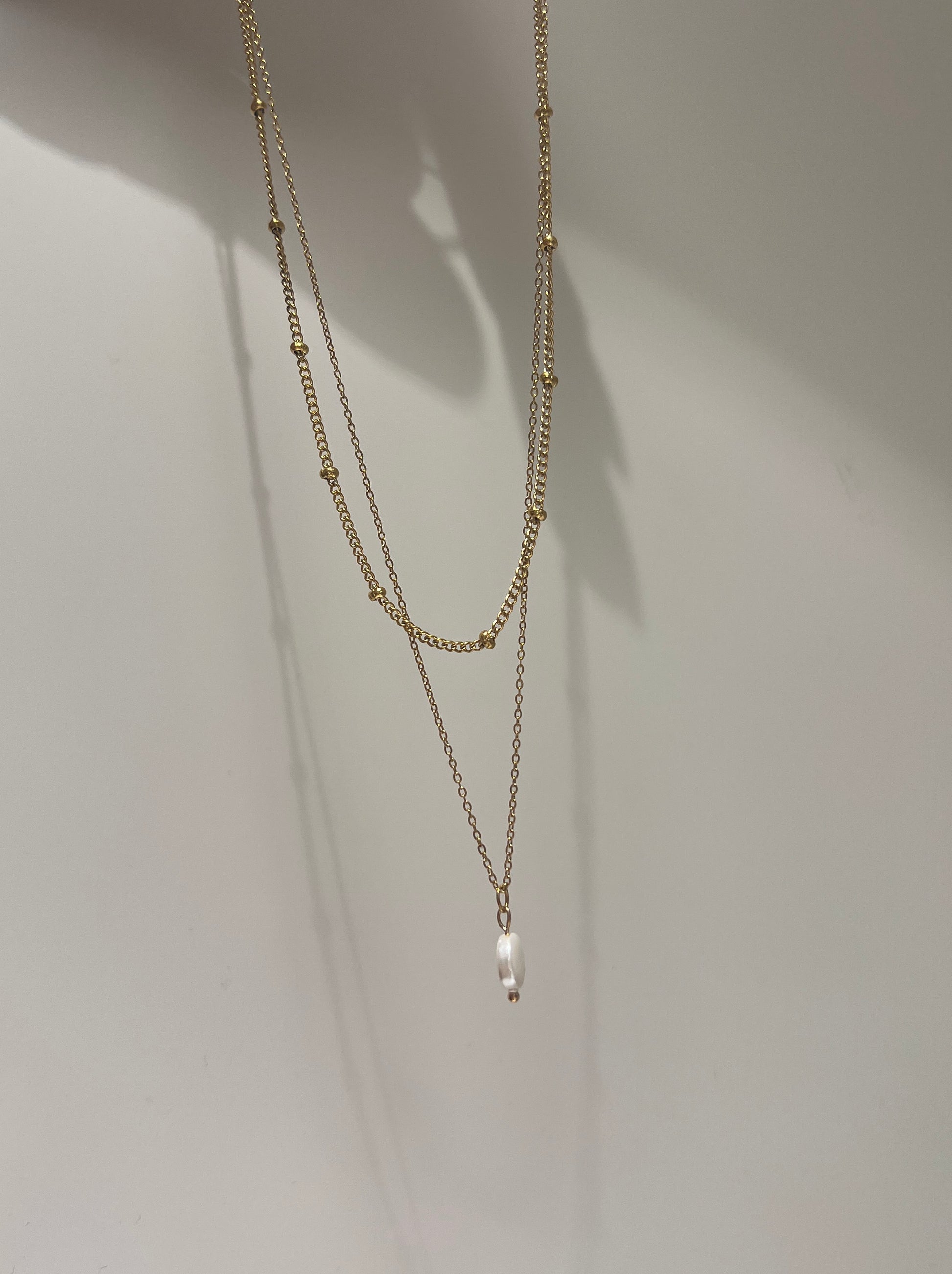 Two gold necklaces on a white background